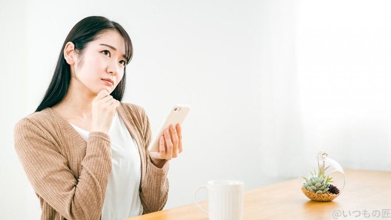 スマホを見ながら考える女性